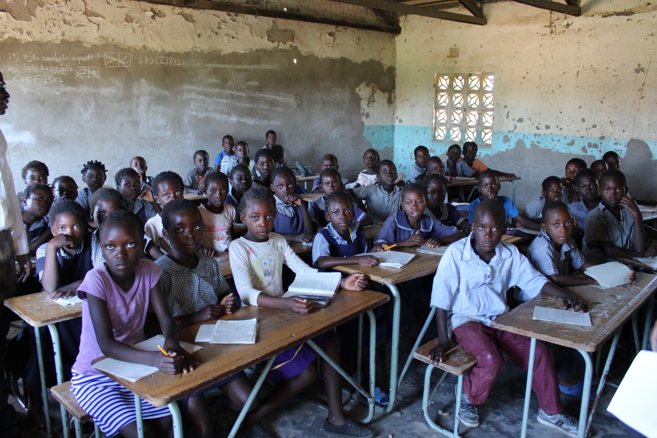 A group of children in a classroom in Zambia focused on their studies.